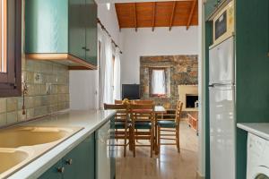 a kitchen with green cabinets and a table and chairs at Liakoto Villa with private pool and jacuzzi in Makry Gialos