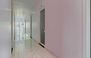 BhauliHotel O Mb Garden & Resorts的有白色墙壁、门和大理石地板的走廊
