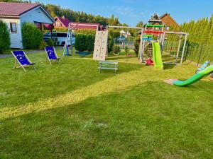 a playground with a slide and chairs on the grass at Anida Rusinowo in Rusinowo