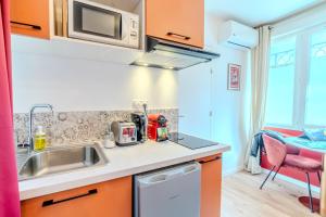 a kitchen with a sink and a microwave at Prestige Jacuzzi & Clim, parking - Roanne centre-ville in Roanne