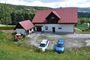 a barn with two cars parked in front of it at Penzion Hainiš in Janske Lazne