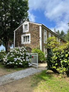 a brick house with flowers in front of it at Hotel Rural La Casa del Burrero in Castropol