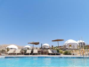 una piscina con sedie a sdraio e ombrelloni di Timlalin Dome a Tamri