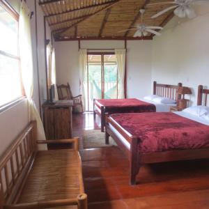 a room with three beds with red sheets at Hotel Lara's Planet in El Castillo de La Concepción