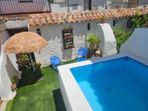 a swimming pool with two chairs and an umbrella at Casa rural El Patio con chimenea, barbacoa, piscina, patios exteriores para sus mascotas de manera gratuita in Benadalid