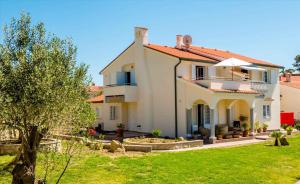 ein großes weißes Haus mit einem grünen Hof in der Unterkunft Apartment Banjol 23 in Rab