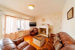 a living room with a leather couch and a fireplace at Holiday House Nova in Blato