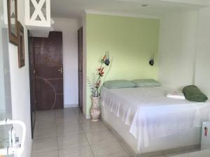 a bedroom with a white bed and a vase with flowers at pousada do rei in Pedra de Guaratiba