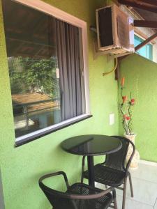 een tafel en twee stoelen naast een groene muur bij pousada do rei in Pedra de Guaratiba