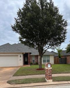 a house with a tree in the front yard at Farmhouse Charm in College Station