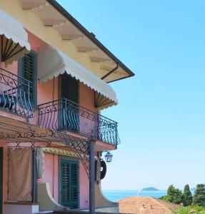 a pink building with balconies and the ocean in the background at Locanda Miranda in Tellaro