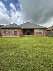 a brick house with a lawn in front of it at Farmhouse Charm in College Station