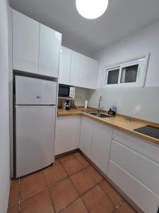 eine Küche mit weißen Schränken und einem Kühlschrank in der Unterkunft 8i Ocean Front Playa 4 in San Bartolomé de Tirajana
