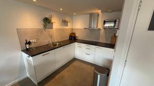 a small kitchen with white cabinets and a sink at De Kajuit in Westkapelle