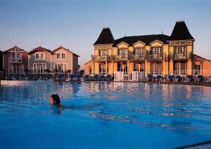 a woman swimming in a pool in front of a house at Appartement l'Archipel - Vue mer exceptionnelle et bassins aquatiques du 29 avril au 15 sept in Talmont