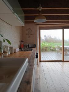 une cuisine avec vue sur une terrasse avec une porte coulissante en verre dans l'établissement maison bretonne plage à pied, à Plouhinec