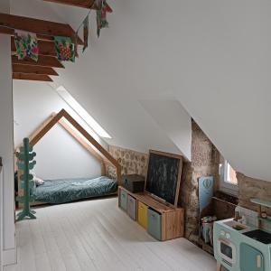 une chambre mansardée avec un lit et une télévision dans l'établissement maison bretonne plage à pied, à Plouhinec