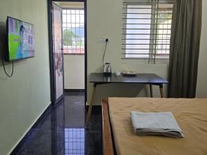 a room with a bed and a table and a television at Perumal home stay in Tiruvannāmalai