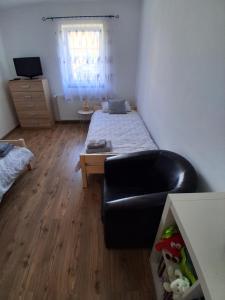 a bedroom with a bed and a black leather couch at GABE Vendègház in Gyöngyöstarján