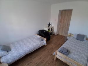 a bedroom with two beds and a chair in it at GABE Vendègház in Gyöngyöstarján