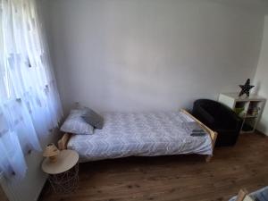 a small bedroom with a bed and a chair at GABE Vendègház in Gyöngyöstarján
