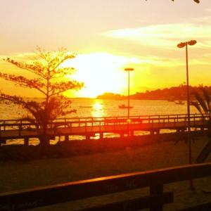 a sunset over a body of water with a bridge at pousada do rei in Pedra de Guaratiba