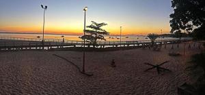 a sandy beach with a pier and the ocean at sunset at pousada do rei in Pedra de Guaratiba