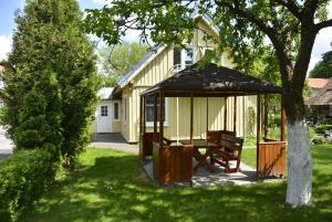a gazebo with a bench in front of a house at Neringaholiday Apartamentai in Juodkrantė