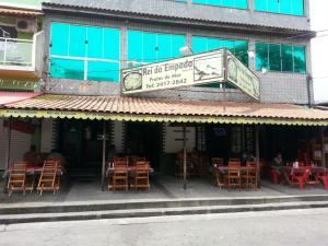 a restaurant with tables and chairs in front of a building at pousada do rei in Pedra de Guaratiba