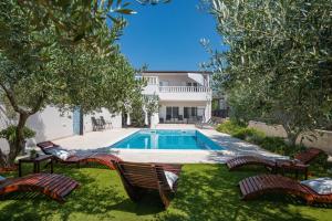 a swimming pool in a yard with chairs and a house at Beachfront villa Mihovil with direct beach access in Kastel Stafilic