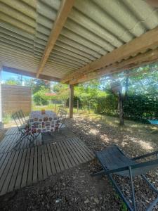 a patio with a table and chairs under a roof at Petite maison proche Marais Poitevin, Puy dufou in La Ronde