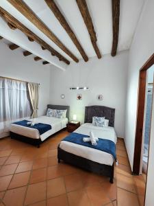 2 bedden in een kamer met witte muren en houten plafonds bij Apartamento de la Villa II in Villa de Leyva