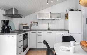 a kitchen with white cabinets and a table with chairs at Holiday Home Bjerregårdsvej Hvide Sande Ds Denm in Bjerregård +19 photos