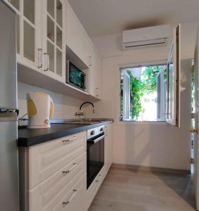 a kitchen with white cabinets and a sink and a window at Apartment Povljana 1 in Povljana