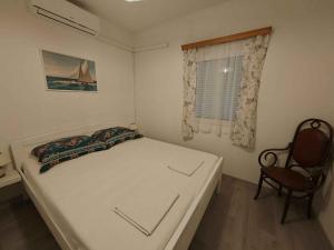 a small bedroom with a bed and a chair at Apartment Povljana 1 in Povljana