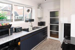 a kitchen with blue cabinets and a sink at Luxury Virginia Water 3BR near Thorpe Park & Heathrow in Virginia Water