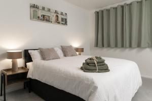 a bedroom with a bed with white sheets and a window at Luxury Virginia Water 3BR near Thorpe Park & Heathrow in Virginia Water