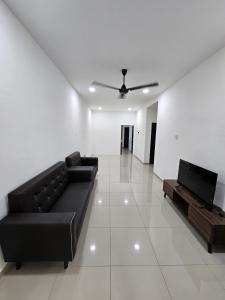 a living room with a black couch and a tv at Green View Homestay in Kuantan