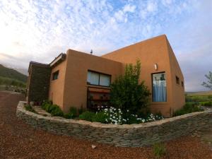 une maison brune entourée d'un mur de pierre dans l'établissement AlteVrede Olive Farm, à Doornrivier