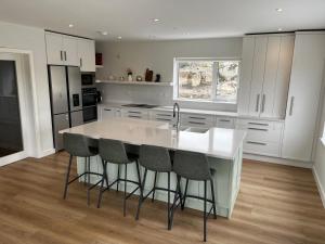a kitchen with a white island with bar stools at Dooneen House in Clifden
