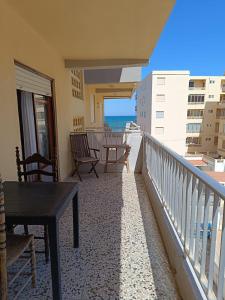 Un balcón con sillas y una mesa y el océano. en Cozy Beachside Apartment, en Tavernes de Valldigna
