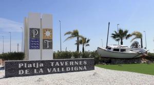 a sign on the beach with a boat in the background at Cozy Beachside Apartment in Tavernes de Valldigna