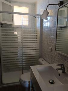 Un baño con inodoro, lavabo y espejo. en Cozy Beachside Apartment, en Tavernes de Valldigna 8 fotos más