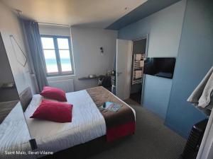 a bedroom with a bed with red pillows on it at Hôtel Ar Iniz in Saint Malo