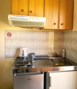 a kitchen with a stove and a sink and a microwave at Skala Eresos Paradise Studios in Skala Eresou