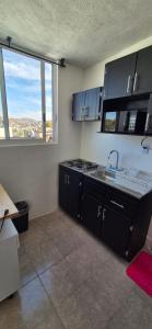 a kitchen with black cabinets and a sink and windows at Deptos Lago de Guadalupe in Mexico City