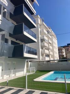 un bâtiment avec une piscine devant dans l'établissement Gandia Playa Moderna - nuevo con piscina y parking, 2 banos, playa 300 m, grau 300 m, à Playa de Gandia