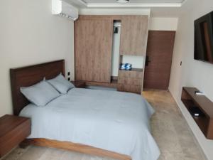 a bedroom with a white bed with a wooden headboard at Turix 102 in Puerto Morelos