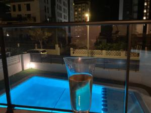 a glass of water sitting next to a swimming pool at Gandia Playa Moderna - nuevo con piscina y parking, 2 banos, playa 300 m, grau 300 m in Playa de Gandia
