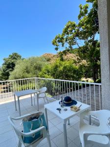 a patio with two tables and chairs on a balcony at SAINT FLORENT studio terrasse 2 à 3 personnes calme avec piscine au sel in Saint-Florent